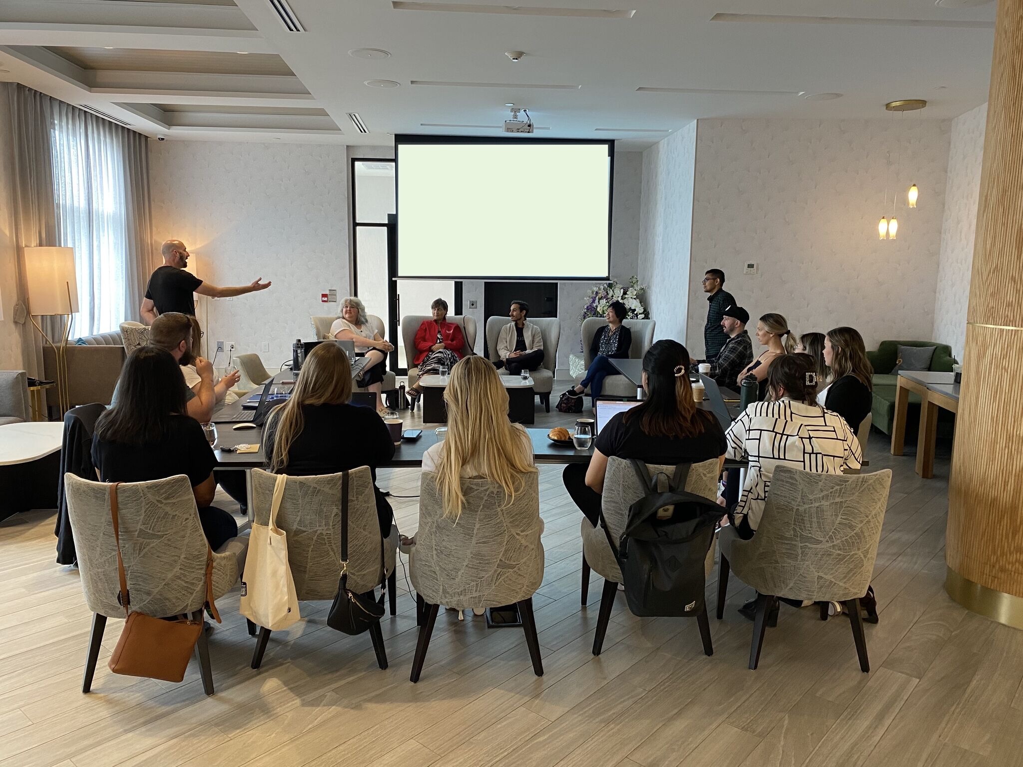Ron Grinblat standing and gesturing as he leads a small business panel session for a seated room of about fifteen attendees.
